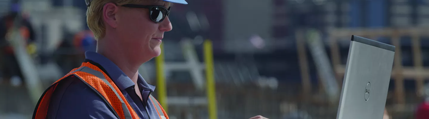 femme portant un casque sur un chantier de construction avec un ordinateur portable