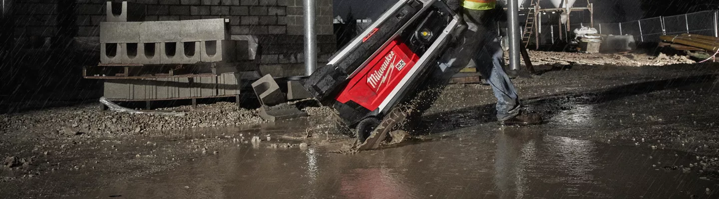 Travailleur tirant une tour d’éclairage sous la pluie