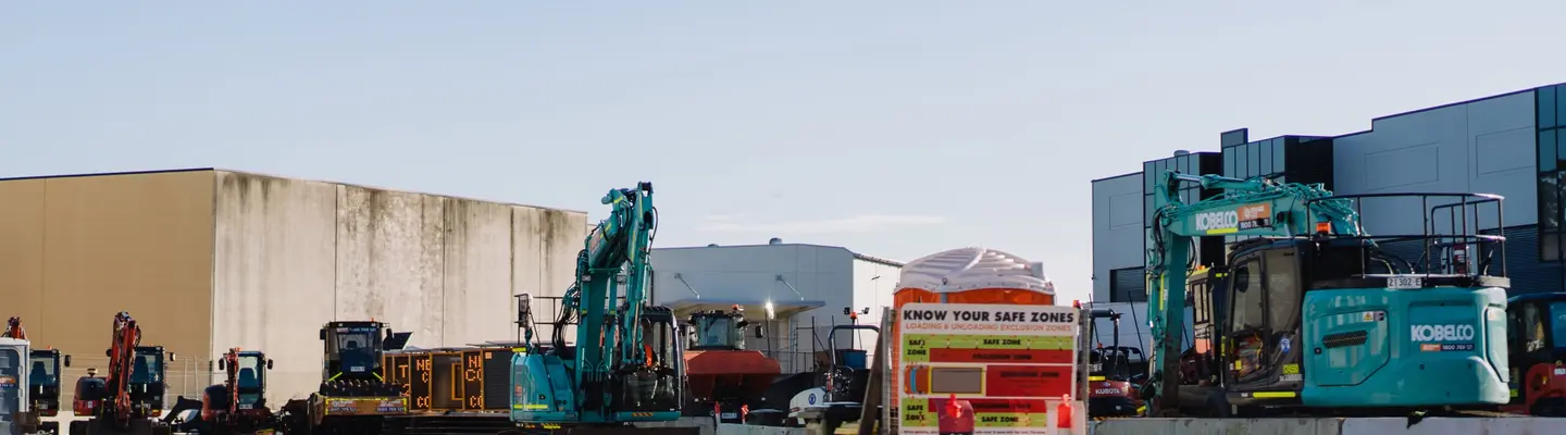 Chantier de construction avec divers équipements, camion-citerne pulvérisant le contrôle de la poussière et barrières de sécurité remplies d’eau en place.