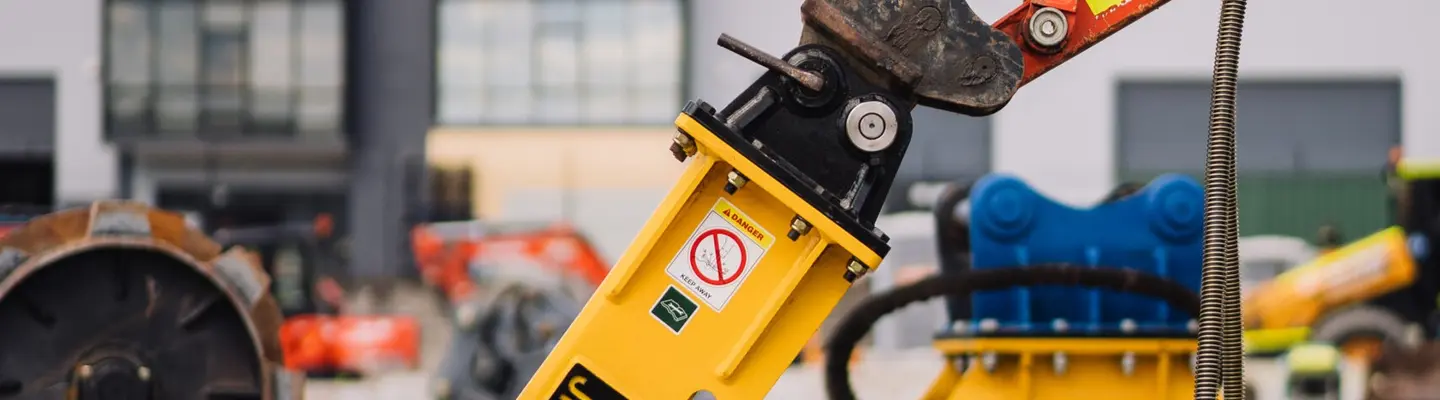 excavatrice avec perceuse à l’extrémité, utilisée pour briser le sol sur un chantier de construction avec des mesures de sécurité en place.