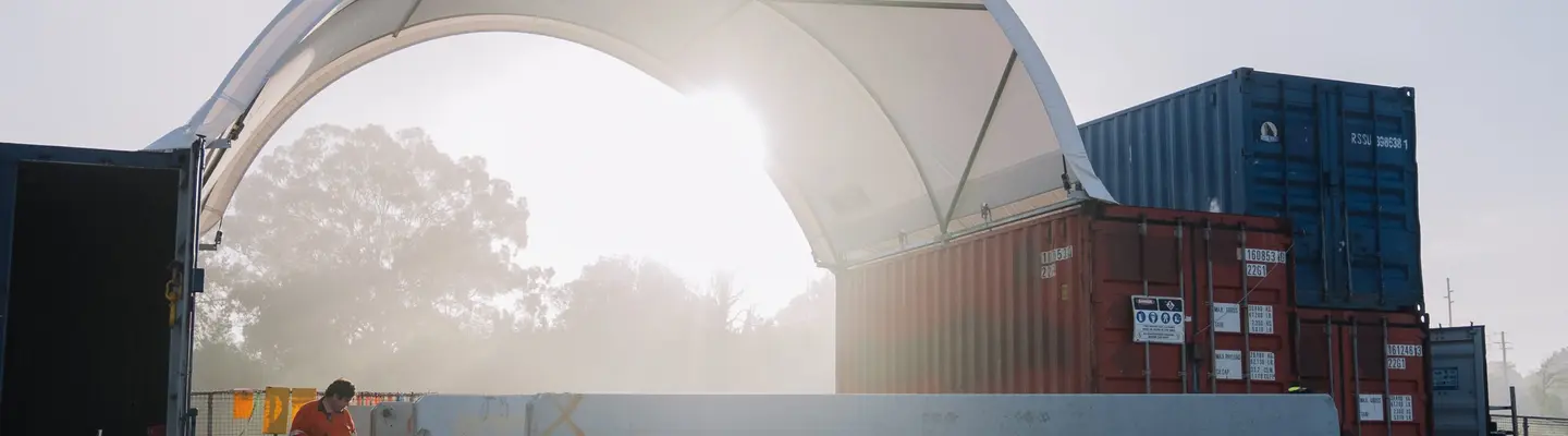 Homme ajustant diverses barrières de sécurité avec de l’équipement portatif sur un chantier de construction, mettant l’accent sur la configuration de la sécurité au travail.