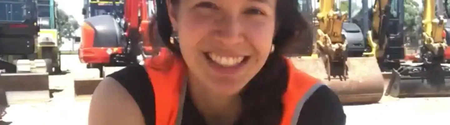 Natasha Haddad devant des excavatrices sur un chantier de construction, mettant en valeur l’équipement et l’équipe d’Orange Hire.