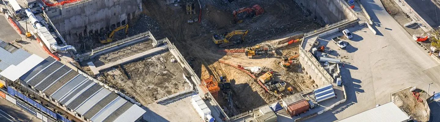 Divers équipements de construction travaillant le long d’une rive pour construire et renforcer une ligne de chemin de fer avec des barrières de sécurité.
