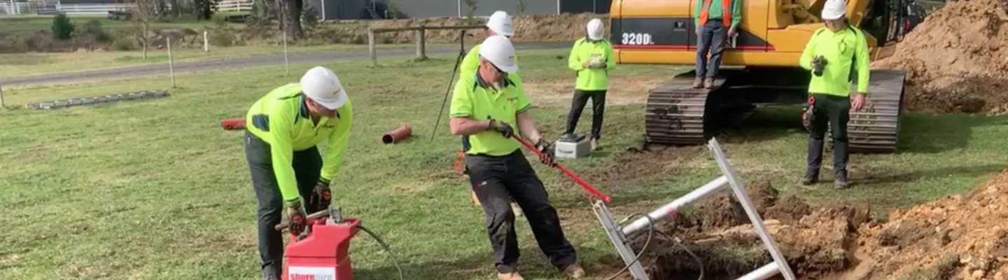 Les travailleurs de la construction creusent une tranchée et placent des supports métalliques dans le sol, en suivant les procédures de sécurité appropriées.