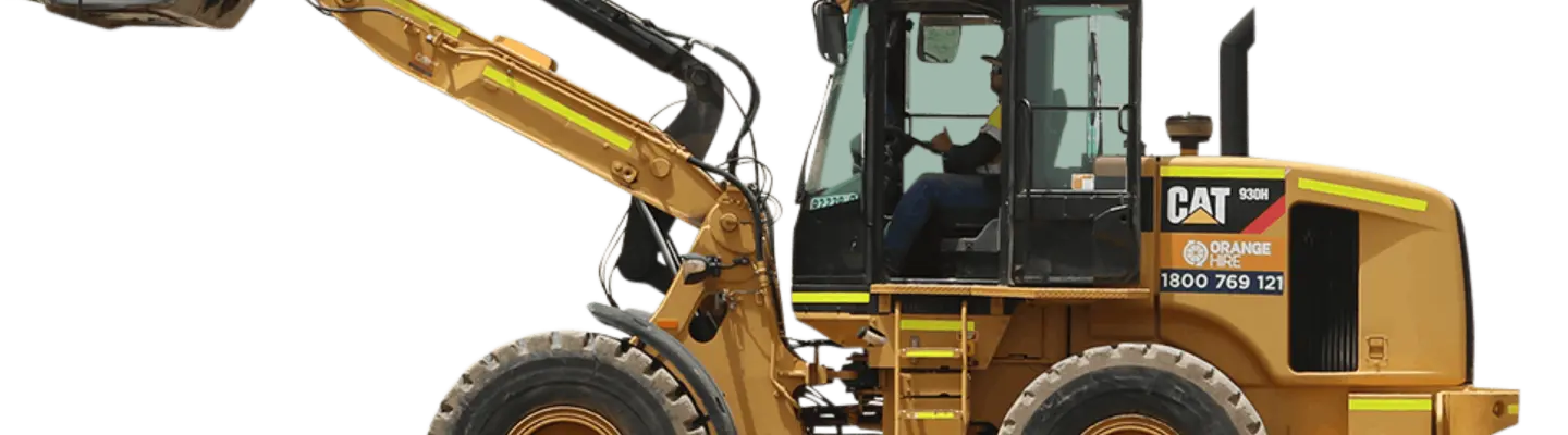 Homme conduisant une rétrocaveuse sur un chantier de construction, avec des barrières de sécurité et de l’équipement visibles en arrière-plan.