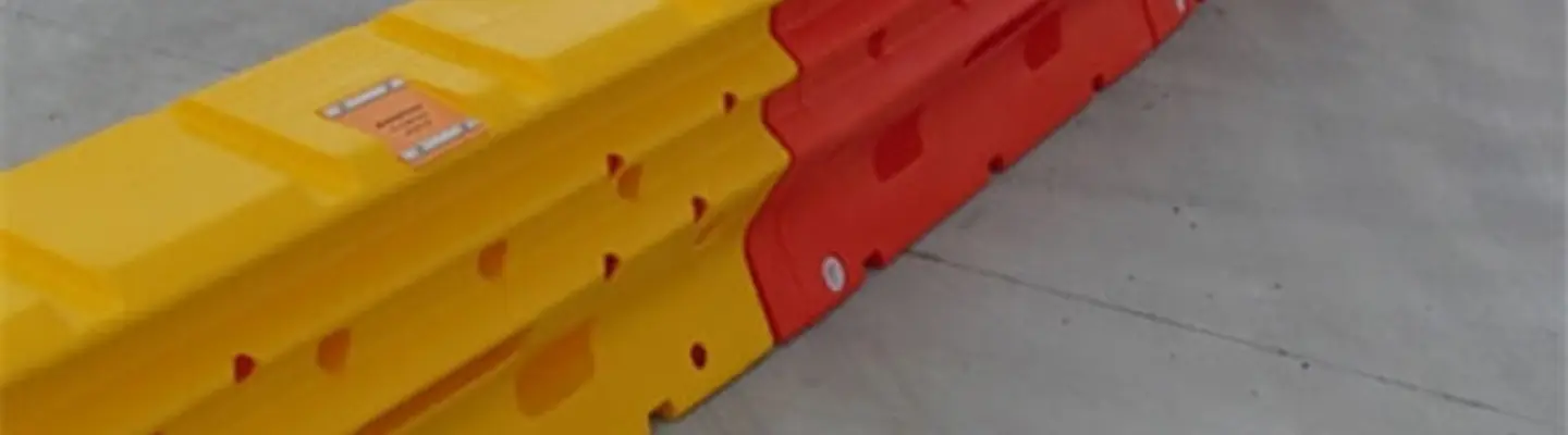 Barrières de sécurité remplies d’eau alignées le long d’un chantier de construction routière pour gérer la circulation et protéger les travailleurs.