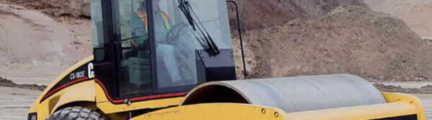 Rouleau de compactage Caterpillar utilisé sur un chantier de construction, compactant le sol pour préparer une fondation stable pour les travaux routiers.