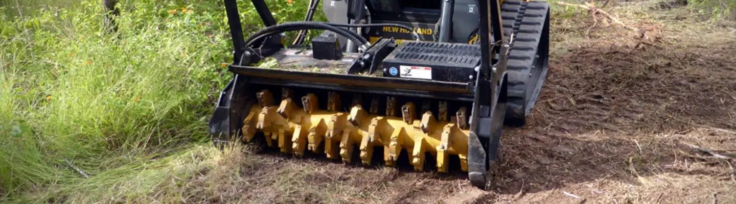 Grande machine qui coupe de l’herbe surélevée dans un champ ouvert près des barrières routières pour soutenir la sécurité et la visibilité routières.