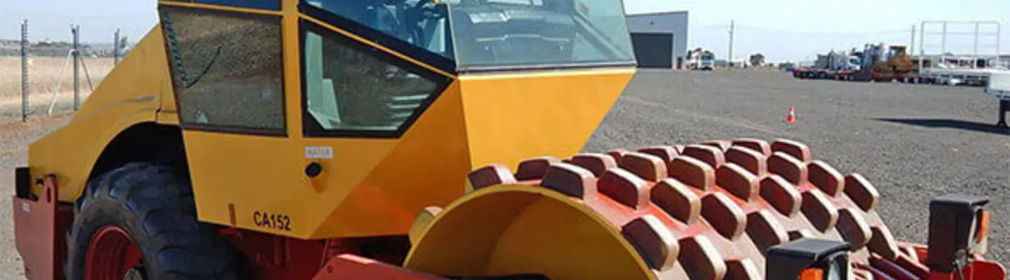 Photo d’une machine à rouleaux sur un chantier de construction, entourée de barrières de sécurité et d’une signalisation pour la prévention des dangers.