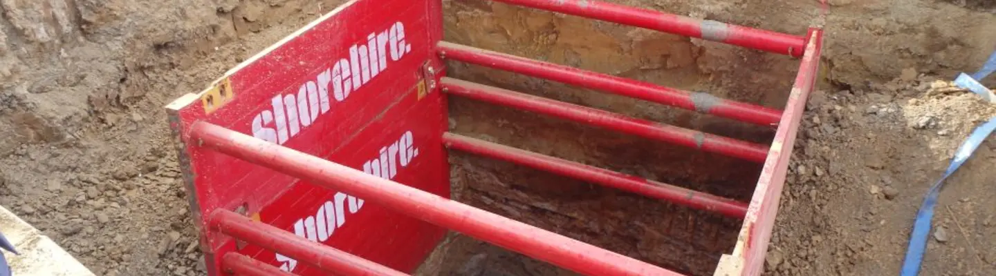 Les travailleurs installant des accessoires internes à l’intérieur d’une boîte d’étayage placée dans une tranchée pour renforcer les murs d’excavation et maintenir la sécurité.