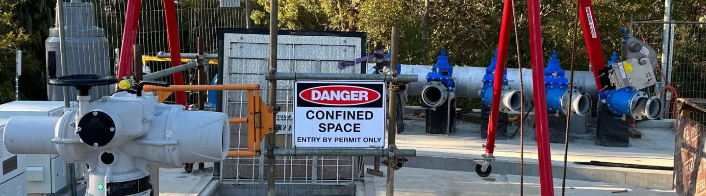 Chantier de construction avec divers matériaux dispersés et un panneau d’avertissement indiquant un espace clos dangereux pour la sensibilisation à la sécurité.