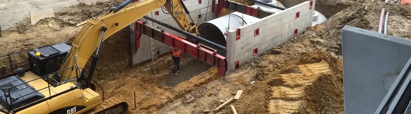 Plusieurs machines et équipements excavant le sol sur un chantier de construction, préparant le sol pour la construction de fondations ou d’infrastructures.