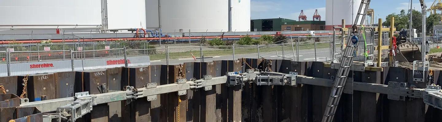 Travailleur de construction installant des systèmes de renfort hydraulique dans une tranchée pour prévenir l’effondrement des murs et améliorer la sécurité de l’excavation.