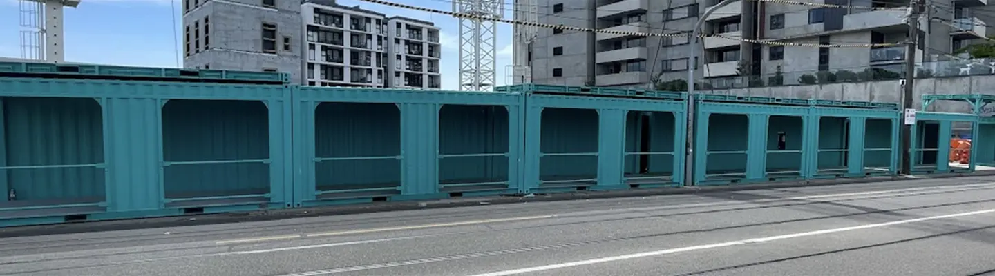 Une passerelle couverte pour conteneurs sur le chantier de construction, offrant un accès et une séparation sécuritaires des piétons des zones de travail actives.