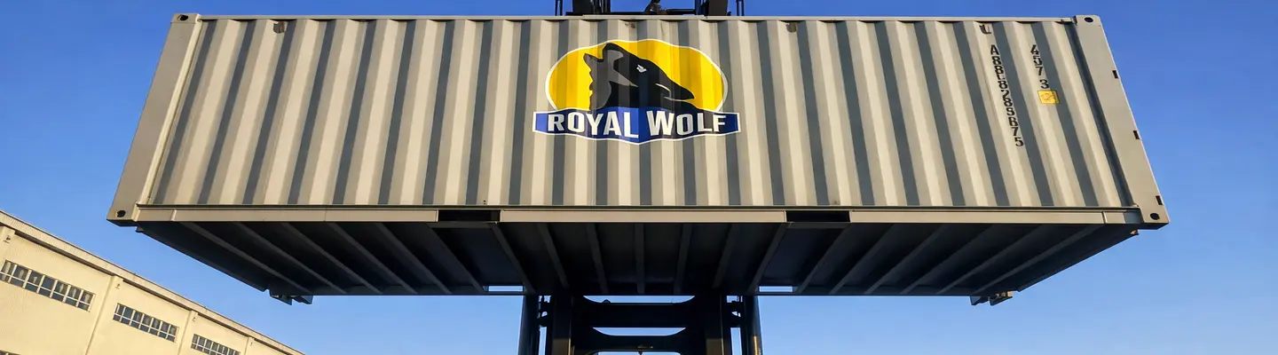 Un conteneur d’expédition Wolf-lock de 6 mètres soulevé par un chariot élévateur, suspendu au-dessus du sol dans une cour industrielle.