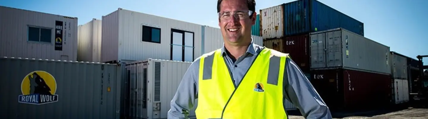 Le directeur se tient devant une pile de conteneurs d’expédition sur un chantier, supervisant les opérations de logistique et de sécurité de la construction.