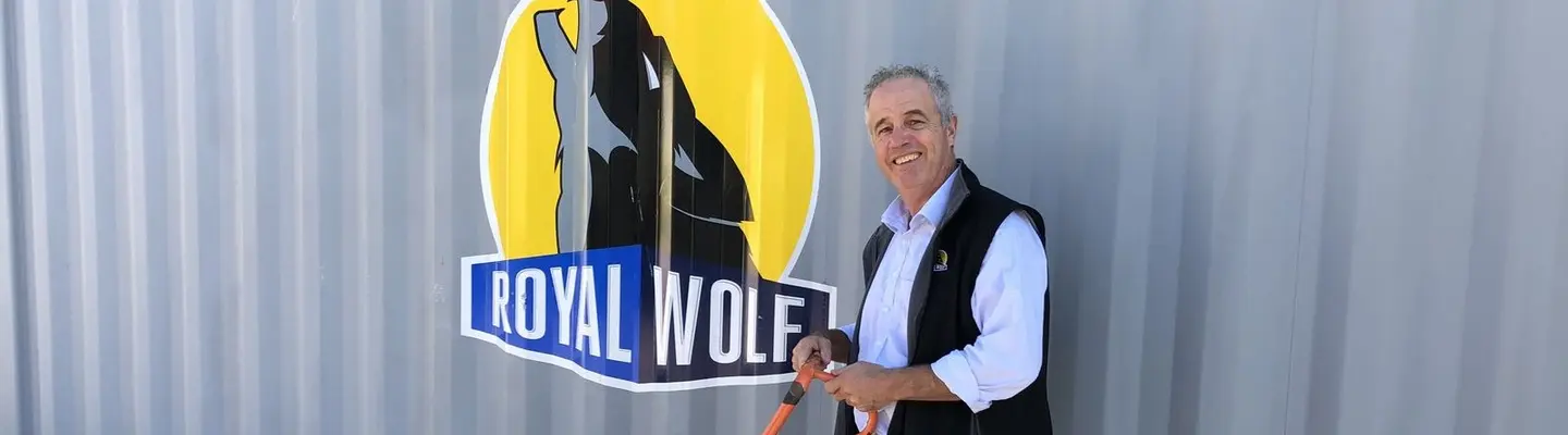 Le directeur se tient devant un conteneur d’expédition sur un chantier de construction, supervisant le placement des barrières et les mesures de sécurité du chantier.