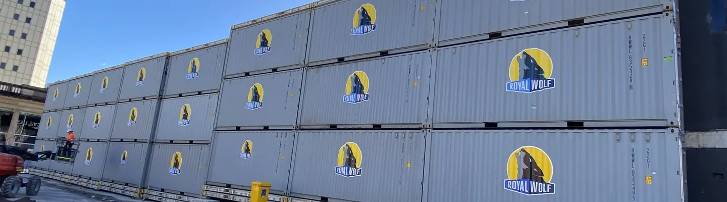 Conteneurs d’expédition empilés organisés et prêts à être utilisés dans un chantier de stockage sécurisé sous un ciel dégagé.