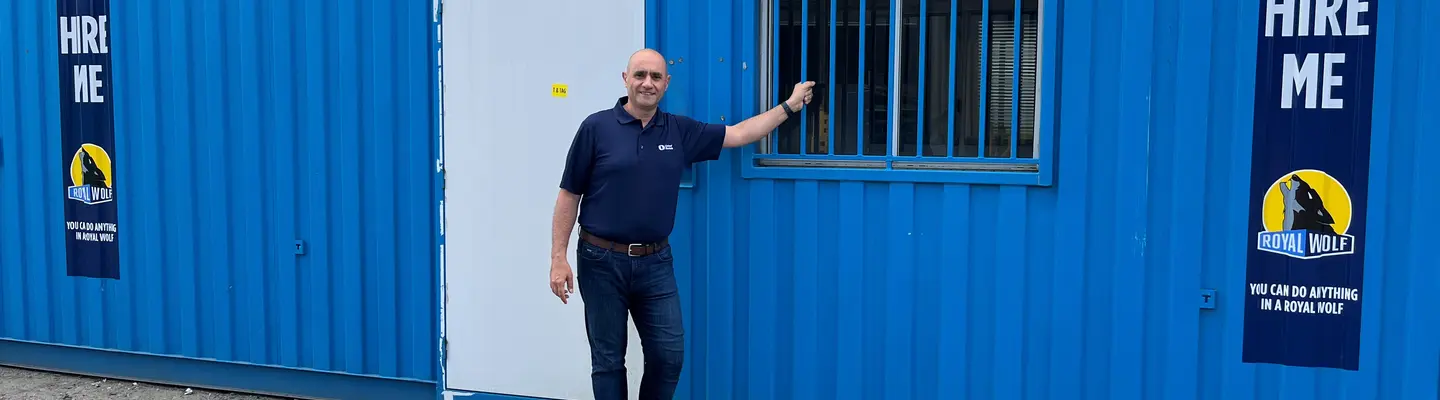 Homme debout devant le conteneur d’expédition bleu du Centre de chantier.