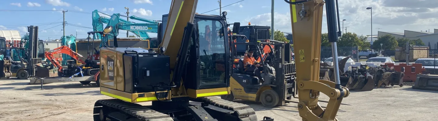 excavatrice stationnée, positionnée près des barrières de sécurité utilisées pour le contrôle du site et la prévention des risques.