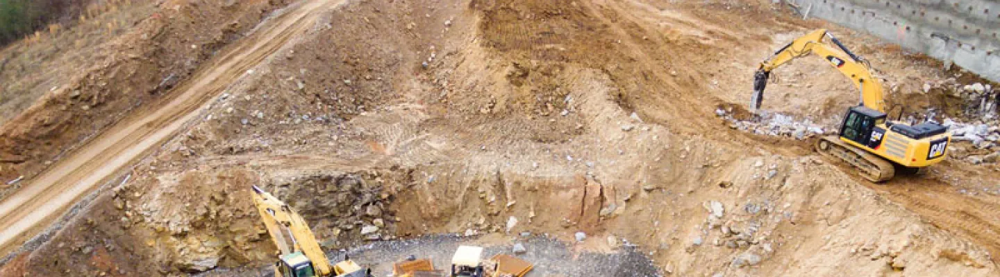 Excavatrices aidant les équipes de construction sur place, avec des barrières de sécurité en place pour contrôler l’accès et protéger les travailleurs.