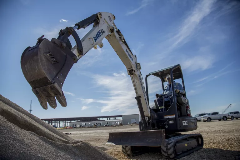 Mini-excavatrice avec bras déployé près du pieu de terre