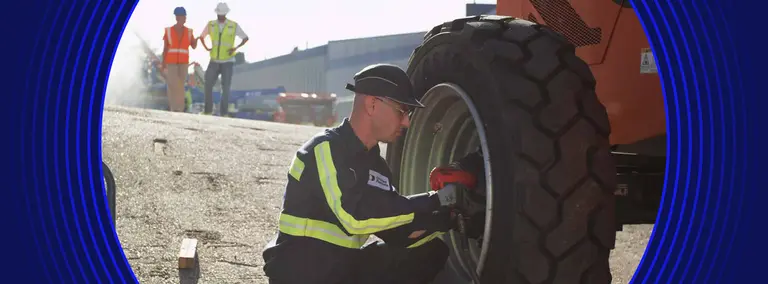 Employé de United Rentals travaillant sur une roue pour une nacelle élévatrice