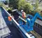 Vue avant inclinée de deux travailleurs en équipement de sécurité utilisant une nacelle élévatrice Genie bleue sur un parking sur le toit.