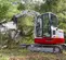 Mini-excavatrice TAKEUCHI blanche, rouge et grise de 3,5 à 4,5 tonnes, balancement réduit de l’arrière