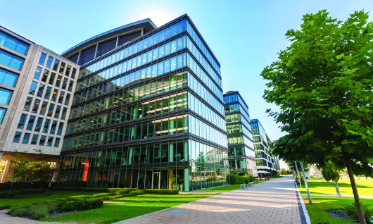 image d’un immeuble de bureaux en verre près d’arbres sous un ciel bleu