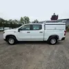 Vue latérale d’une camionnette à cabine double Chevrolet Silverado blanche avec un couvre-lit utilitaire blanc
