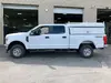Vue latérale d’une camionnette à cabine ronde Chevrolet Silverado blanche avec un bouchon de lit utilitaire blanc.