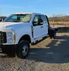 Vue avant droite inclinée d’une camionnette Ford F-350 Super Duty blanche à plateau.