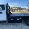 Vue latérale d’une camionnette blanche avec une plaque diamantée noire à plat et des boîtes de stockage visibles en dessous.