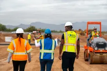 3 people on jobsite walking toward equipment