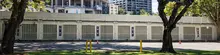 Pedestrian walking past buildings, trees, and a repurposed shipping container, highlighting urban design and green integration.