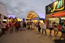 Shipping containers repurposed as vibrant food stalls at a bustling waterfront dining and entertainment precinct.