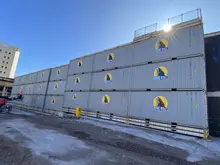 Stacked shipping containers organized and ready for use in a secure storage yard under a clear sky.