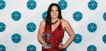 Smiling employee holding an award in front of a company-branded backdrop, recognized for excellence in site safety and barrier services.