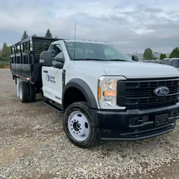 Vue avant gauche inclinée d’une camionnette blanche avec un plateau noir.